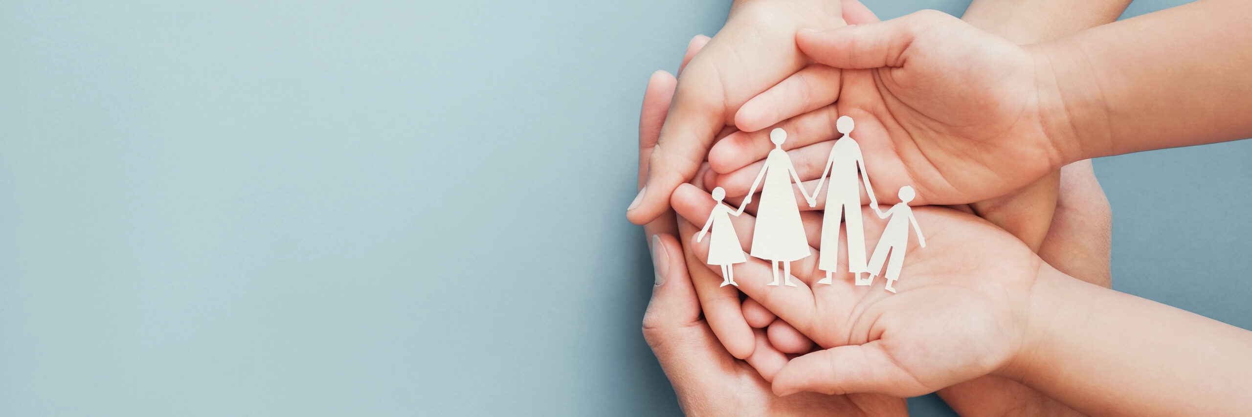 Adult and children hands holding paper family cutout.